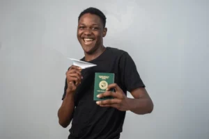 A young worker in uniform holding a “Job Offer” letter and passport, with an airplane in the background